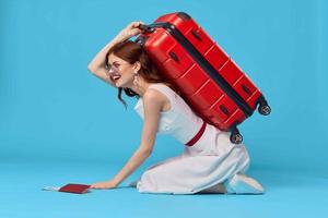 cheerful woman with red suitcase sitting on the floor emotions isolated background photo