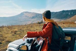 Traveler with a backpack near the car in the mountains in summer and blue sky fresh air photo