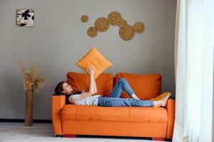 hermosa mujer en el naranja sofá en el descanso habitación posando estilo de vida foto