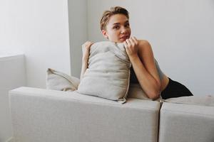 Happy woman smile lying at home on the couch relaxing on a weekend at home with a short haircut hair without filters on a white background, free copy space photo