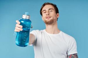 deportivo hombre en blanco camiseta participación azul agua botella en frente de él estudio foto