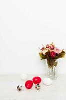 bouquet of fragrant flowers and Easter eggs on a wooden table In a bright room photo