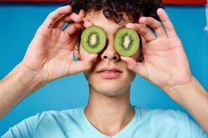 man with curly hair holding kiwi near class face closeup photo