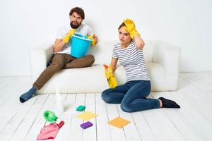 mujer lavados el pisos un hombre se sienta en el sofá a hogar interior limpieza foto
