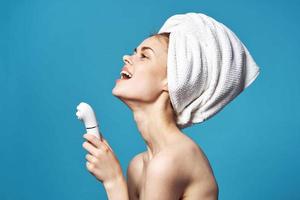 cheerful woman with bare shoulders with a massager in her hands cosmetology dermatology photo