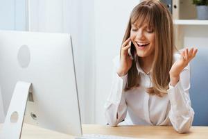 Smiling happy adorable blonde businesswoman worker freelancer talking with client in call in light modern office. Enjoyed employee work on computer online in support service. Copy space photo