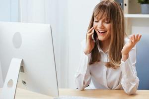 sonriente contento adorable rubia mujer de negocios trabajador persona de libre dedicación hablando con cliente en llamada en ligero moderno oficina. disfruté empleado trabajo en computadora en línea en apoyo servicio. Copiar espacio foto