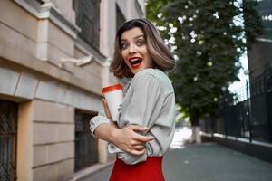 cheerful woman taking a selfie on the street with a cup of coffee photo