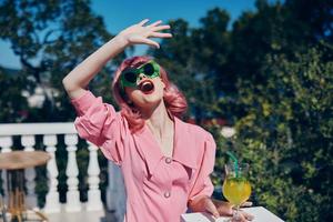 alegre mujer en verde Gafas de sol con cóctel en verano al aire libre Bebiendo alcohol foto