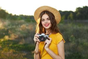 bonito mujer rojo labios encanto sombrero en su cabeza un cámara en el manos de un pasatiempo foto