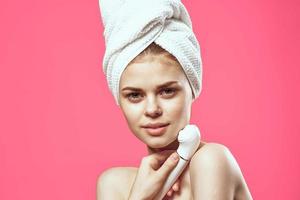 woman with towel on head naked shoulders skin care cosmetology pink background photo