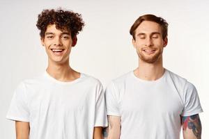 dos alegre amigos en blanco camisetas emociones estudio foto