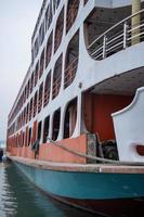 A huge water vessel side view, floating on the river. A big launch at the river dock, floating on the water. Southeast Asian water transportation vessel close-up photo. A modern ship-side view. photo