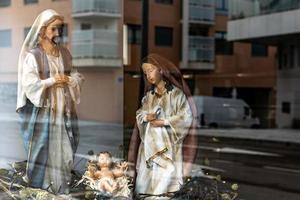 large figures of saints from the nativity scene for Christmas, close to the reflection of the city in the glass photo