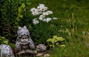 green garden with flowers and plaster figurine natural background photo