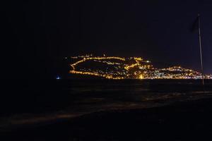 night view of the turkish city of alanya with lights on the hill photo