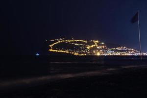 night view of the turkish city of alanya with lights on the hill photo
