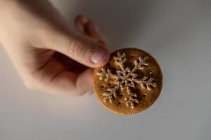l tasty gingerbread with white snowflake decoration for Christmas kept in the hand of a chil photo