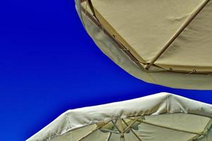 artful background with umbrellas against the backdrop of a blue cloudless sky on a hot summer day at the beach photo