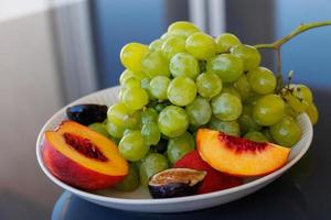 plates with healthy fruit, green grapes, peach, fig photo