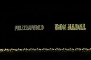 golden shiny neon inscription merry christmas on a black background in Spanish and Catalan, Valencian photo