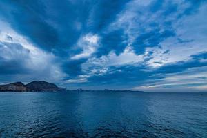 seaside landscape with clouds and sailboat on the horizon Alicante Spain photo