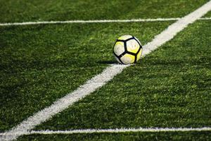 football lying on a green field with artificial turf on a beautiful  day photo