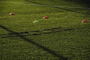 training football pitch with artificial green grass and training aids illuminated by the afternoon  sun photo