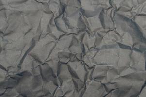 Wrinkled or crumpled black stencil paper or tissue after use in toilet or restroom with large copy space used for background texture in decorative art work photo