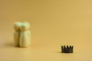 A crown with blur background of group wooden peg dolls. Human resources concept. photo