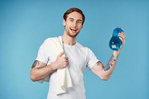 Cheerful sporty man in white t-shirt water bottle energy blue background photo