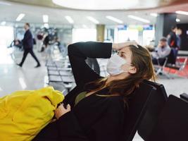 mujer participación su cabeza en médico máscara aeropuerto pasajero esperando para vuelo foto