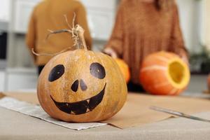 Halloween pumpkin lantern with scary face. Female preparing all hallows eve Halloween party decorations. Background, copy space. selective focus photo