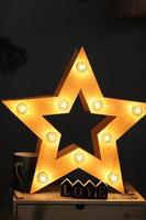 decorative retro star with lots of burning lights, cup and wooden action figures at home. Beautiful decor, modern design element. selective focus photo