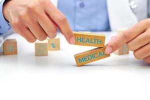 Hand of doctor holding a wooden block cube with text and behind it is a wooden block with blurred icon symbol. Medical and health concept. photo