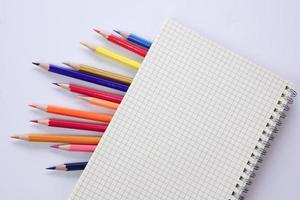 Graph book with colored pencils or pastel lined up on white background. Learning, study and presentation concept. photo