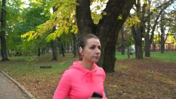 Close up of woman running through an autumn park at sunset video