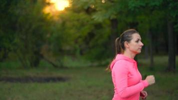 Close up of woman running through an autumn park at sunset video