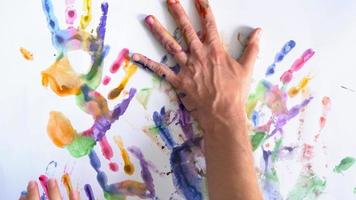 Creative concept - man and woman make prints of their painted hands on a white background video