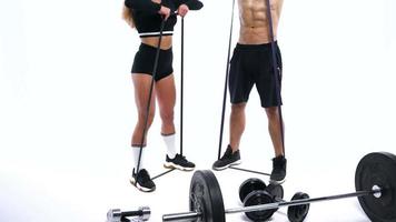 Man flexes his hands with dumbbells, training his shoulders on a white background in the studio video