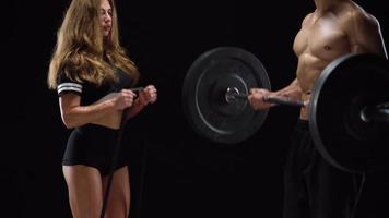 atlético hombre y mujer haciendo ejercicio en el espalda con elástico bandas en un negro antecedentes en estudio video