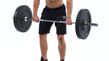 Man flexes his hands with dumbbells, training his shoulders on a white background in the studio video