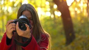 mooi meisje met een camera wandelingen door de herfst Woud en duurt afbeeldingen. weekend buiten de stad video