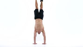 Man flexes his hands with dumbbells, training his shoulders on a white background in the studio video