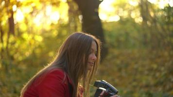 Beautiful girl with a camera walks through the autumn forest and takes pictures. Weekend outside the city video