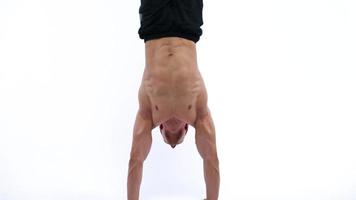 Man flexes his hands with dumbbells, training his shoulders on a white background in the studio video