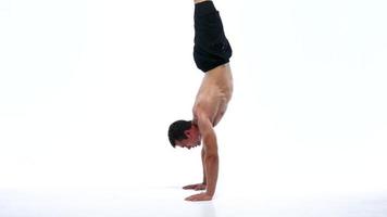 Man flexes his hands with dumbbells, training his shoulders on a white background in the studio video