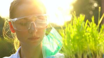 mulher agrônomo dentro óculos e uma mascarar examina uma amostra do solo e plantas video