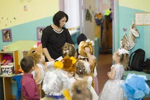 Children from kindergarten go to the Christmas party. Little boys and girls in carnival costumes with a teacher. photo