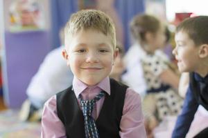 A beautiful child of six. The boy is a primary school student on the background of the class. photo